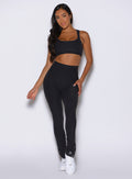 front profile view of a model wearing the Snape Flare Leggings in Heathered Black color paired with the matching bra
