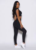 right side profile view of a model looking over her shoulder wearing the Snape Flare Leggings in Heathered Black color