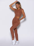 front profile view of a model with one hand resting on top of her head wearing the Snape Flare Leggings in spiced chai color