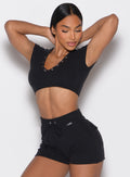 front profile view of a model with both hands on the back of her head wearing the Snap Top in black color