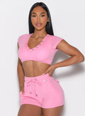 front profile view of a model with one hand on her waist wearing the Snap Top in Pink Cupcake color pared with the matching shorts 