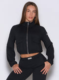 front view of a model with both hands on her thighs wearing the Society Bomber Jacket in black color