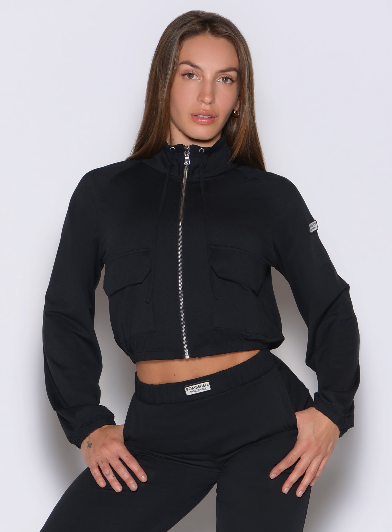 front view of a model with both hands on her thighs wearing the Society Bomber Jacket in black color