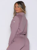 left side profile view of a model looking over her shoulder wearing the Society Bomber Jacket in light mauve color paired with the matching joggers