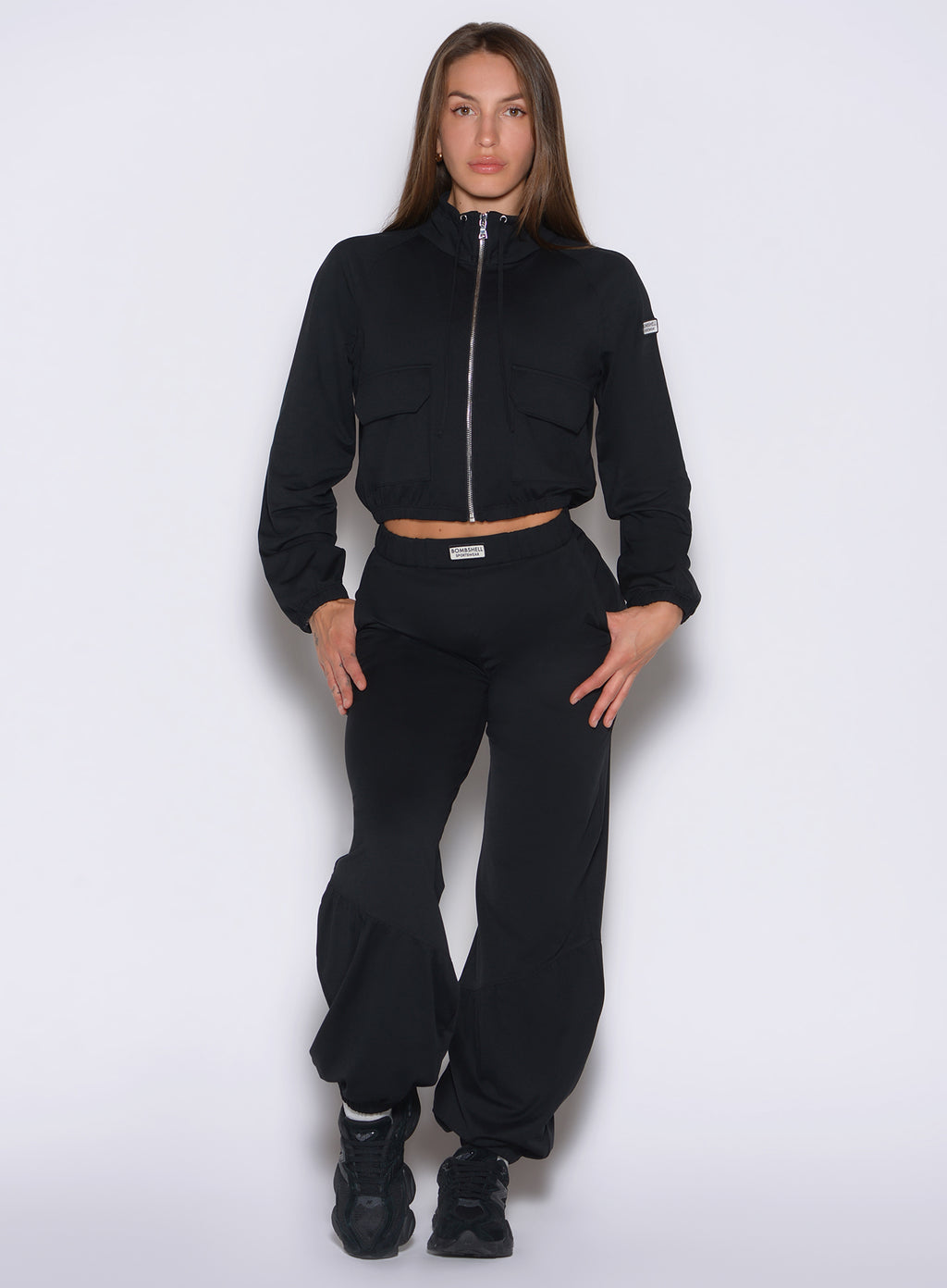 a frontal shot of a model with both hands near the side pockets wearing the society joggers in black color