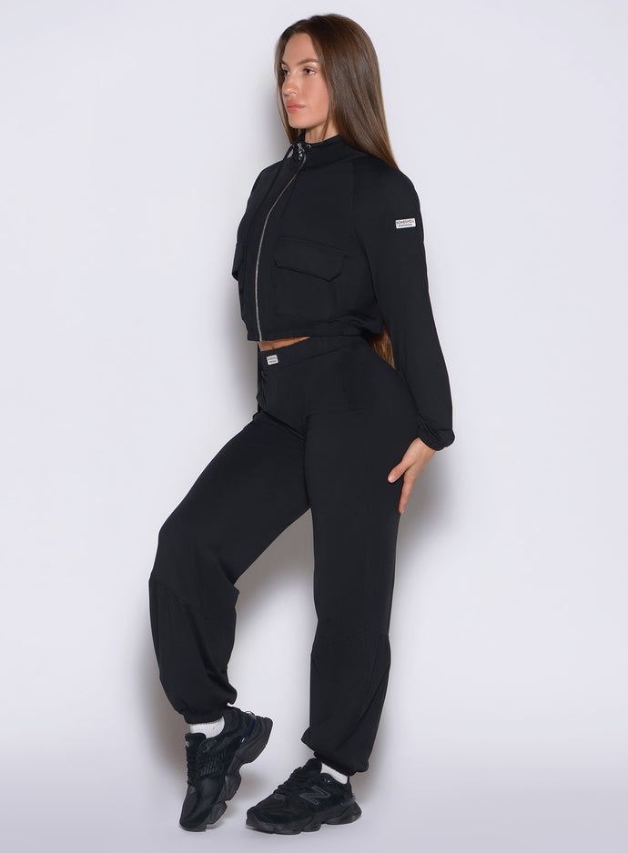 left side profile view of a model wearing the Society Joggers in black color paired with the matching jacket 