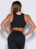 back profile view of a model with both hands on her waist wearing the Society Tank in black color