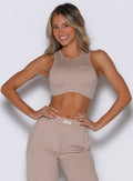 front profile view of a model with both hands on her waist wearing the Society Tank in camel color