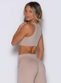 back left side profile view of a model looking over her shoulder wearing the Society Tank in camel color