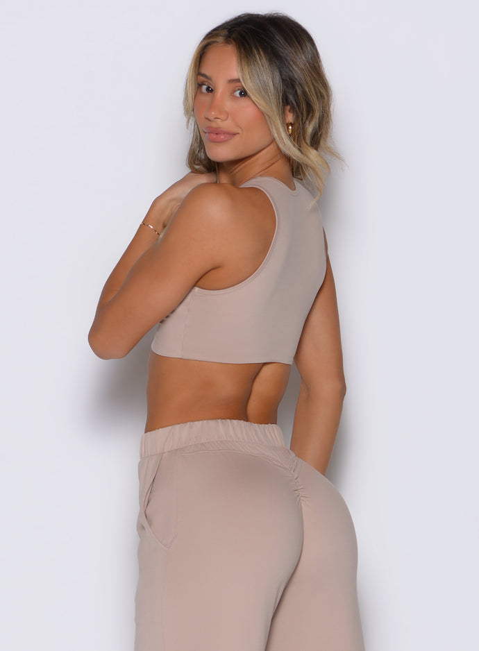 back left side profile view of a model looking over her shoulder wearing the Society Tank in camel color