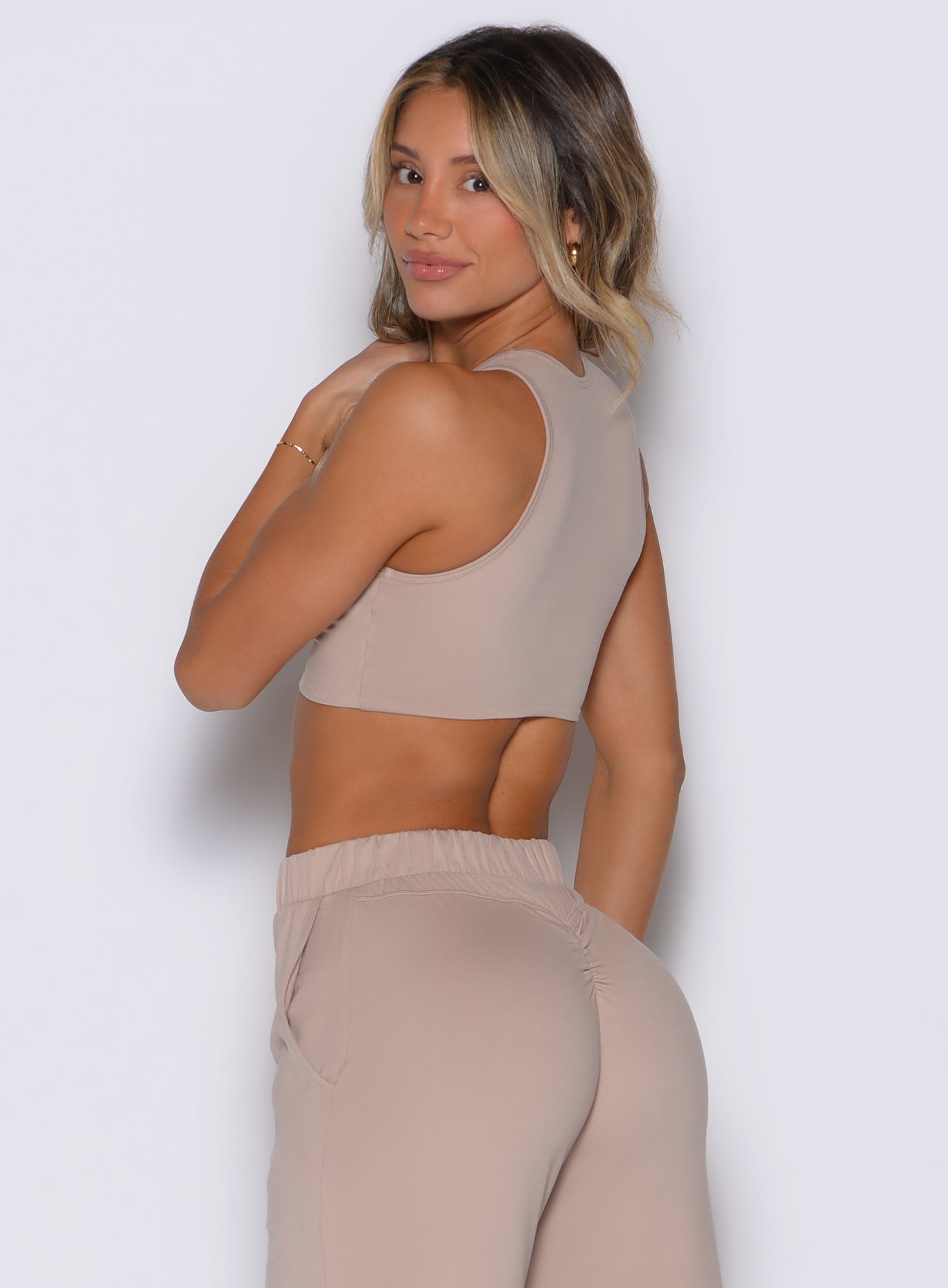 back left side profile view of a model looking over her shoulder wearing the Society Tank in camel color