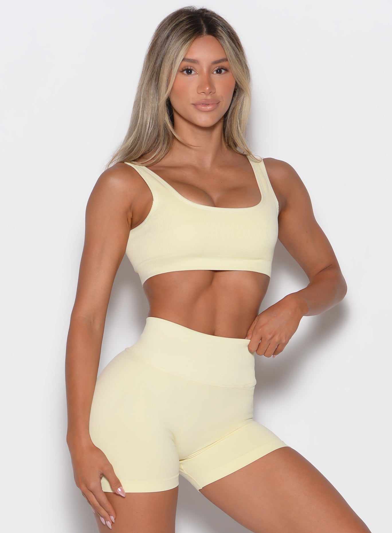 front profile view of a model facing forward wearing our square neck bra in Mellow Yellow color along with a matching pair of shorts