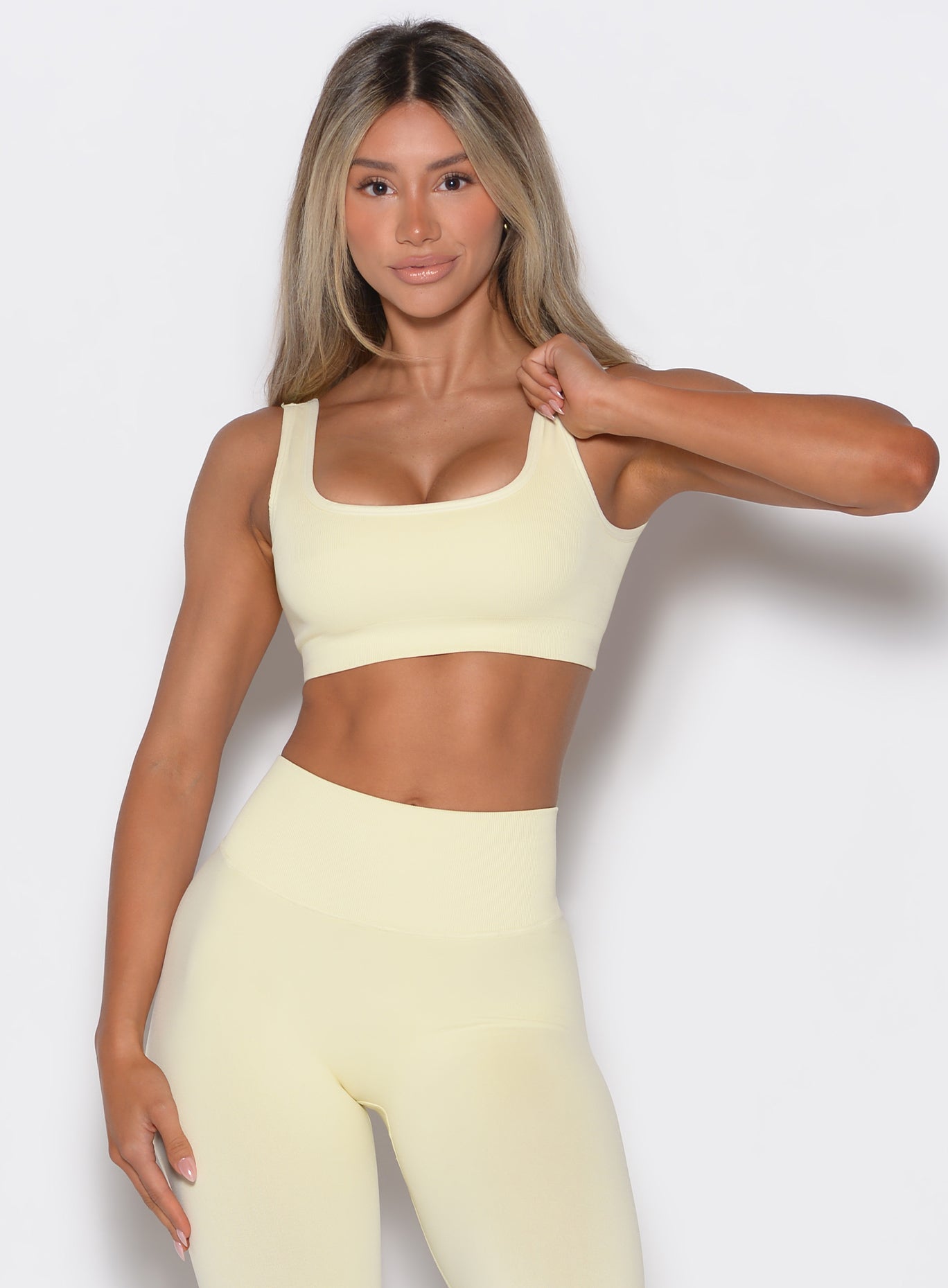 front profile view of a model wearing our square neck bra in Mellow Yellow color along with a matching pair of leggings