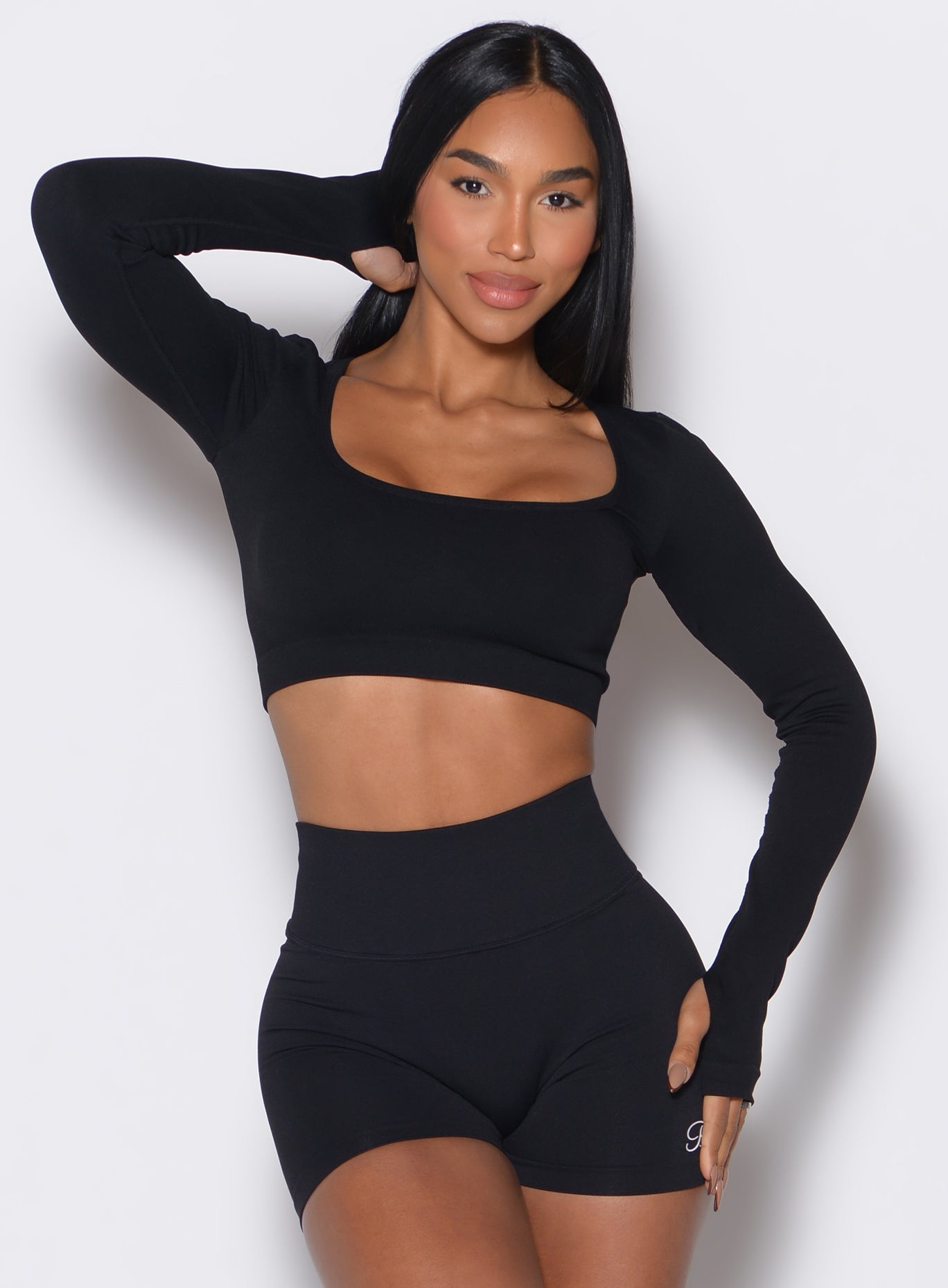 Front profile view of a model wearing our black square neck seamless pullover complemented by a matching shorts 