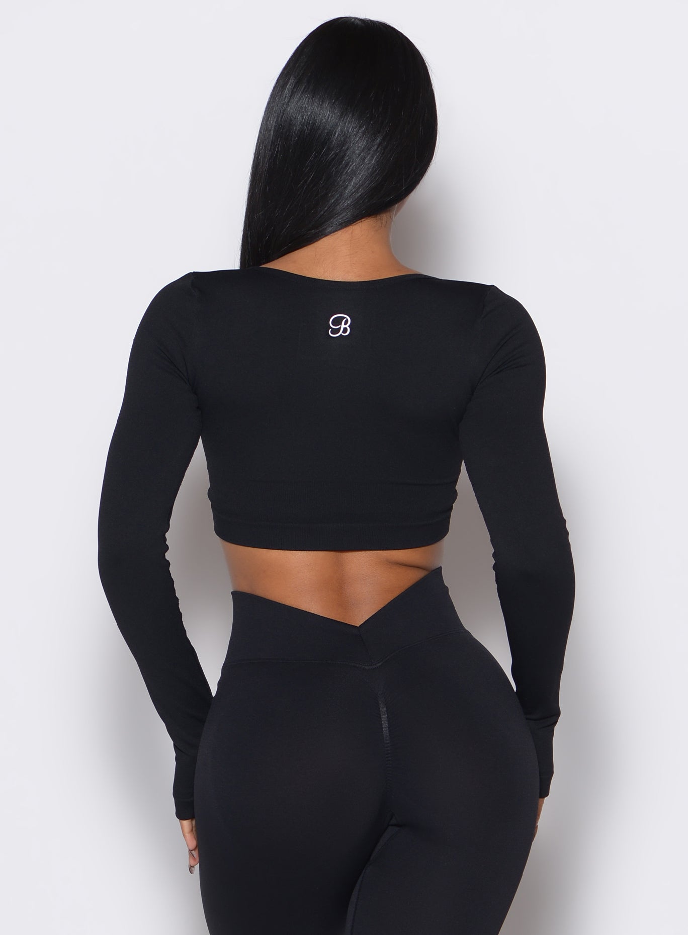 back profile view of a model wearing our black square neck seamless pullover complemented by a matching pair of leggings