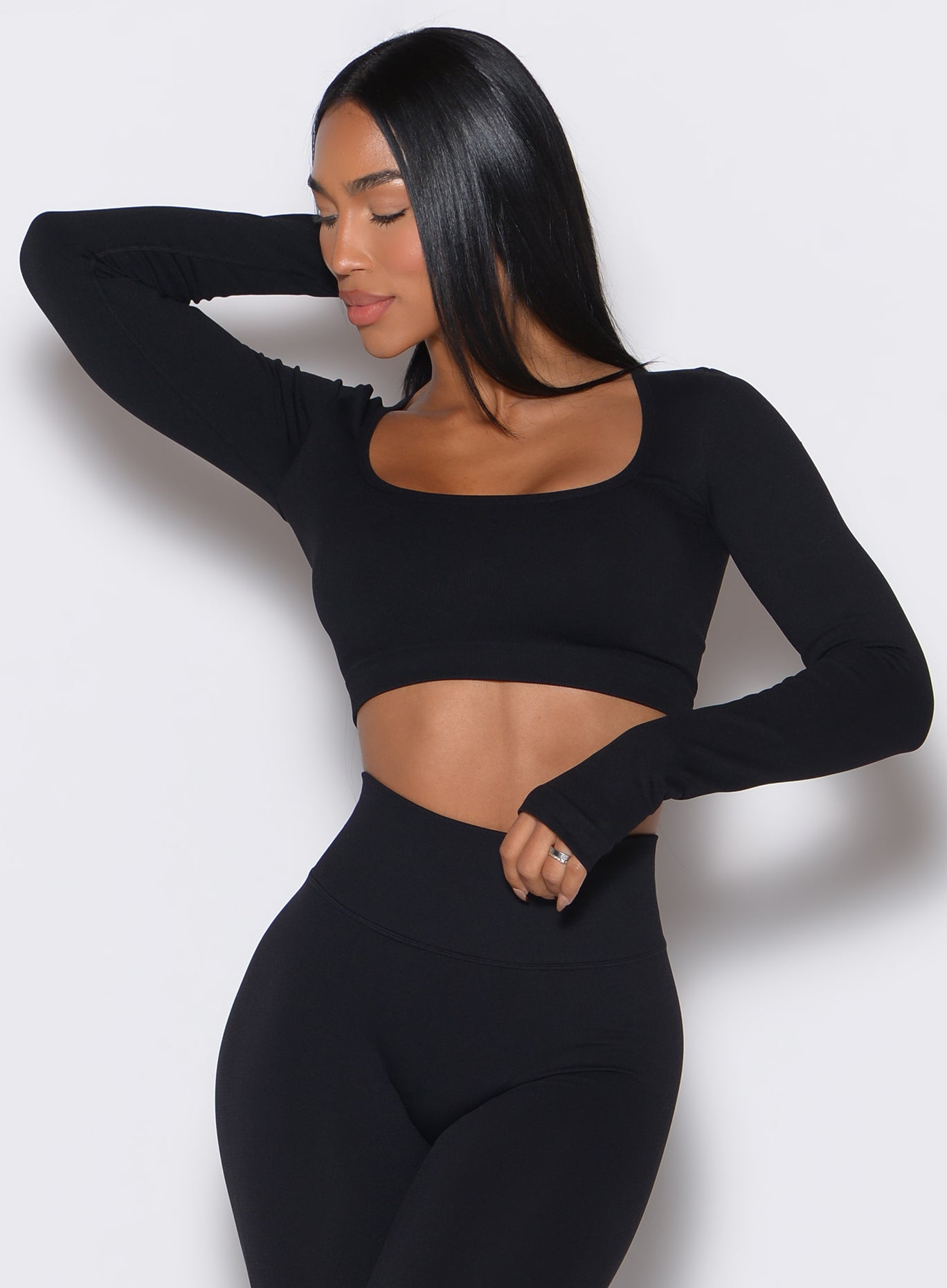 front profile view of a model facing to her right  wearing our black square neck seamless pullover complemented by a matching leggings