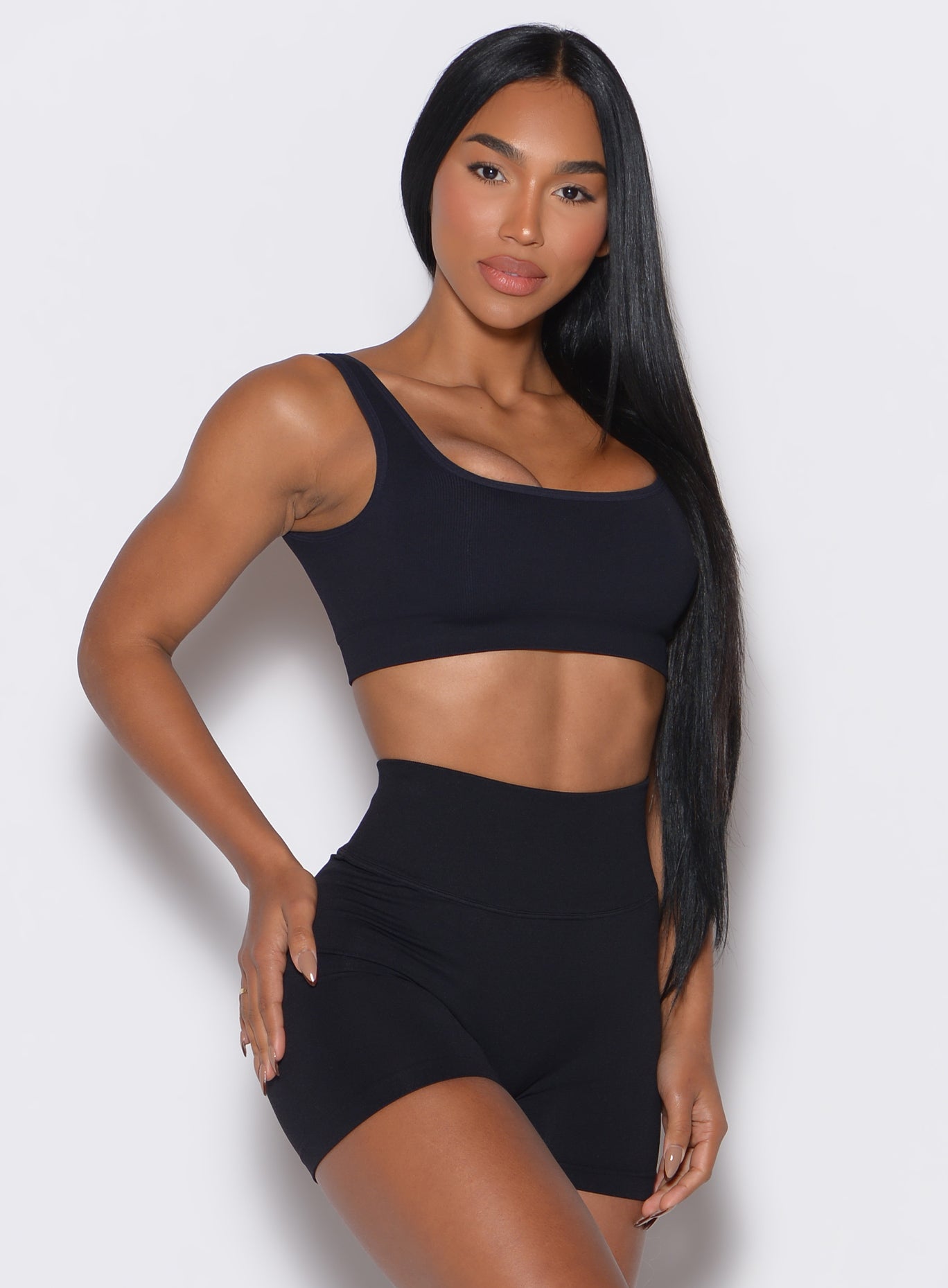right side  profile view of a model angled right wearing our black square neck bra along with the matching shorts