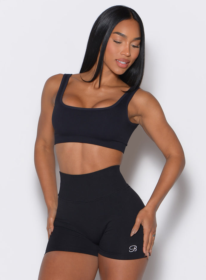 front  profile view of a model wearing our black square neck bra complemented by the matching shorts