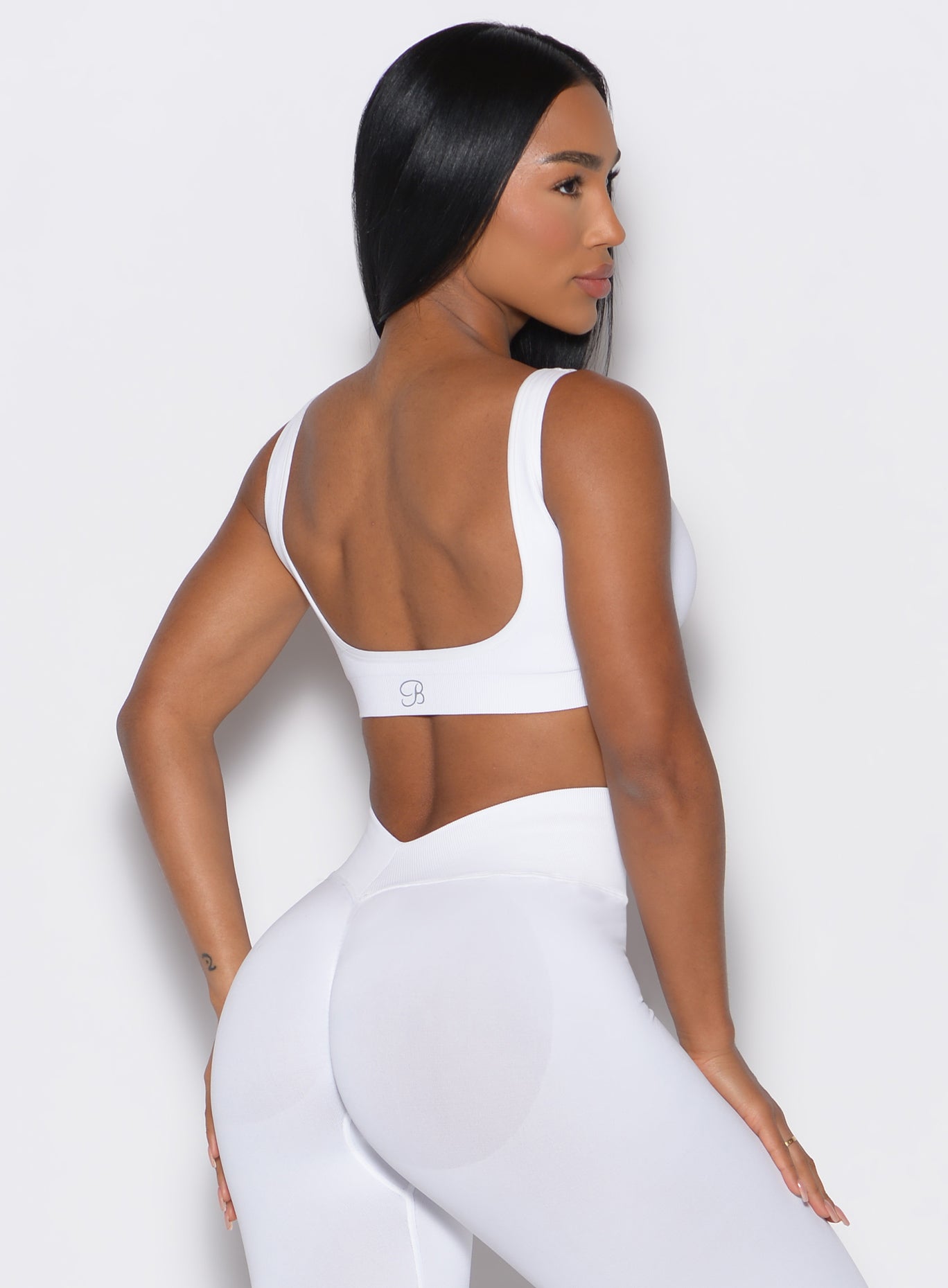 back profile view of a model angled right wearing our white square neck bra along with a matching leggings 