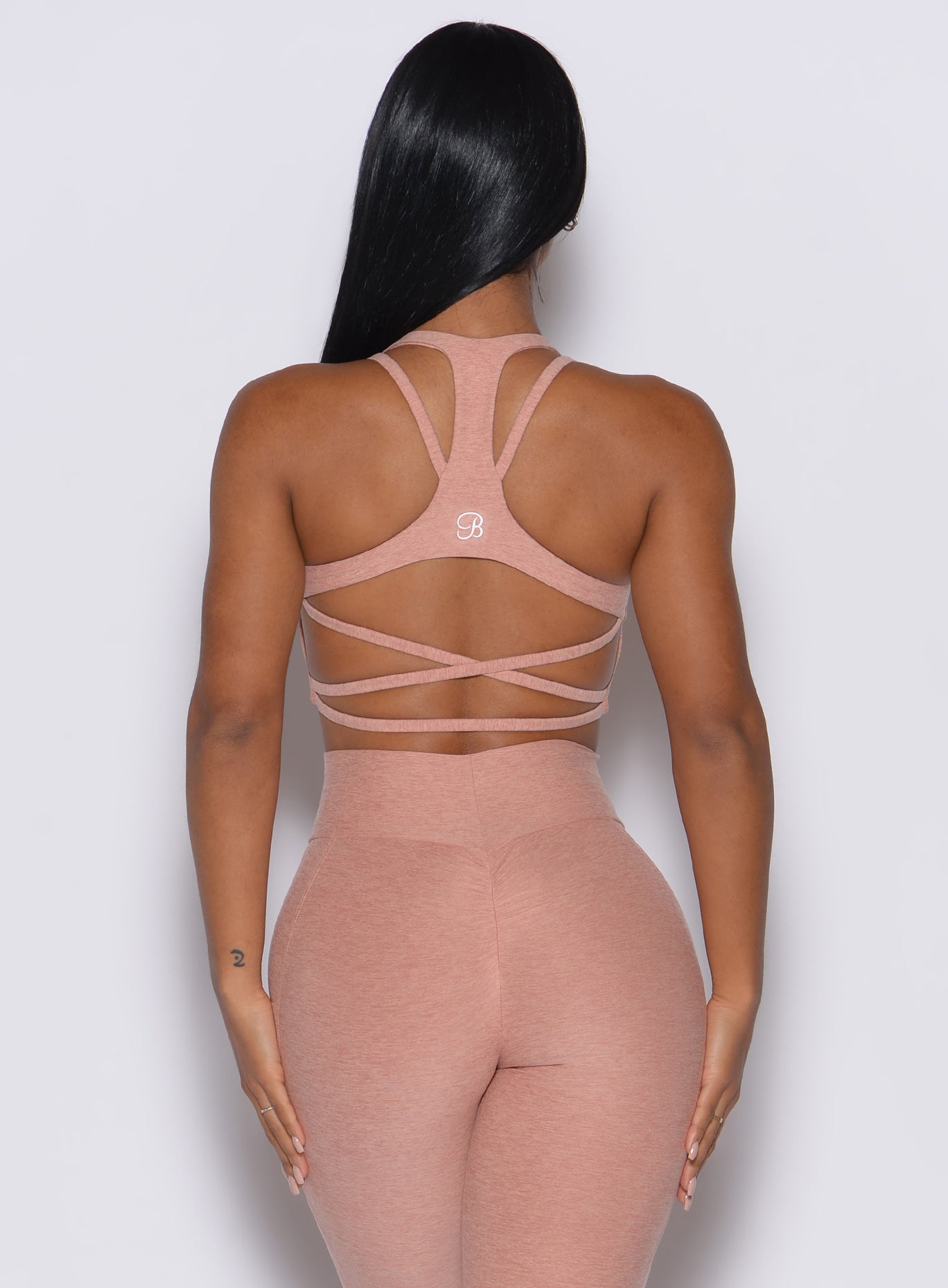 back profile picture of a model wearing our viral tank bra in nude sand color along with the matching leggings