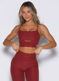 front profile view of a model with both hands on the waistband of the leggings wearing the Studio Sculpt Bra in Rouge color