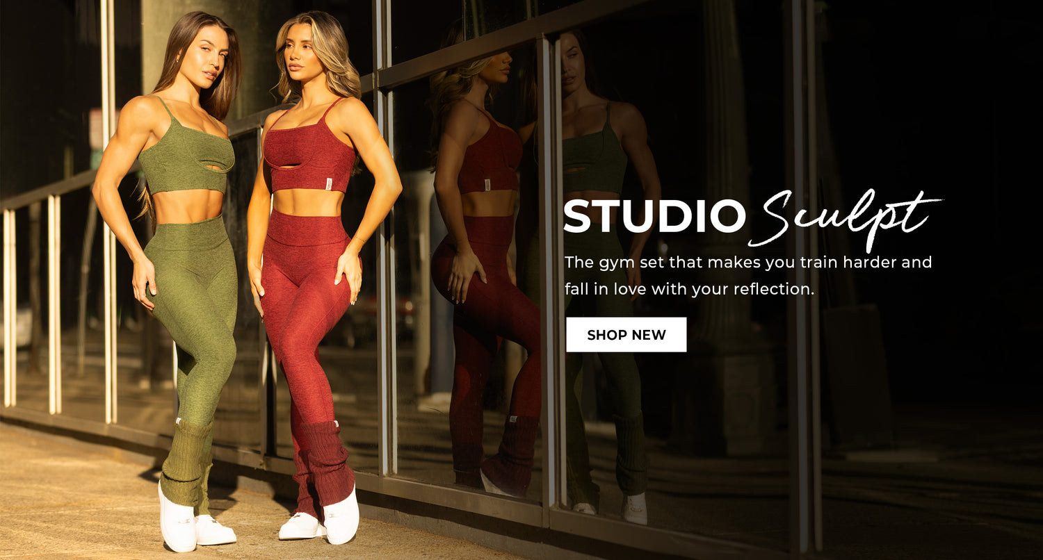 Two women in green and red gym sets standing in front of a mirror with 'Studio Sculpt' collection announcement. Text overlay reads 'The gym set that makes you train harder and fall in love with your reflection.' CTA 'SHOP NEW'