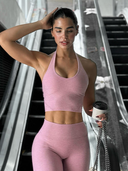 Woman in pink athletic wear holding a coffee cup and handbag.