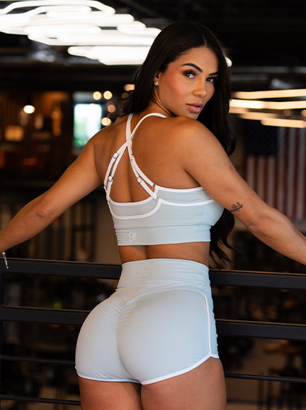 Model wearing a mint blue sports bra and matching athletic shorts.