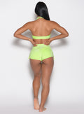 back profile view of a model with both hands on her waist wearing the Sunkissed Sparkle Swim Shorts in Electric Lime color