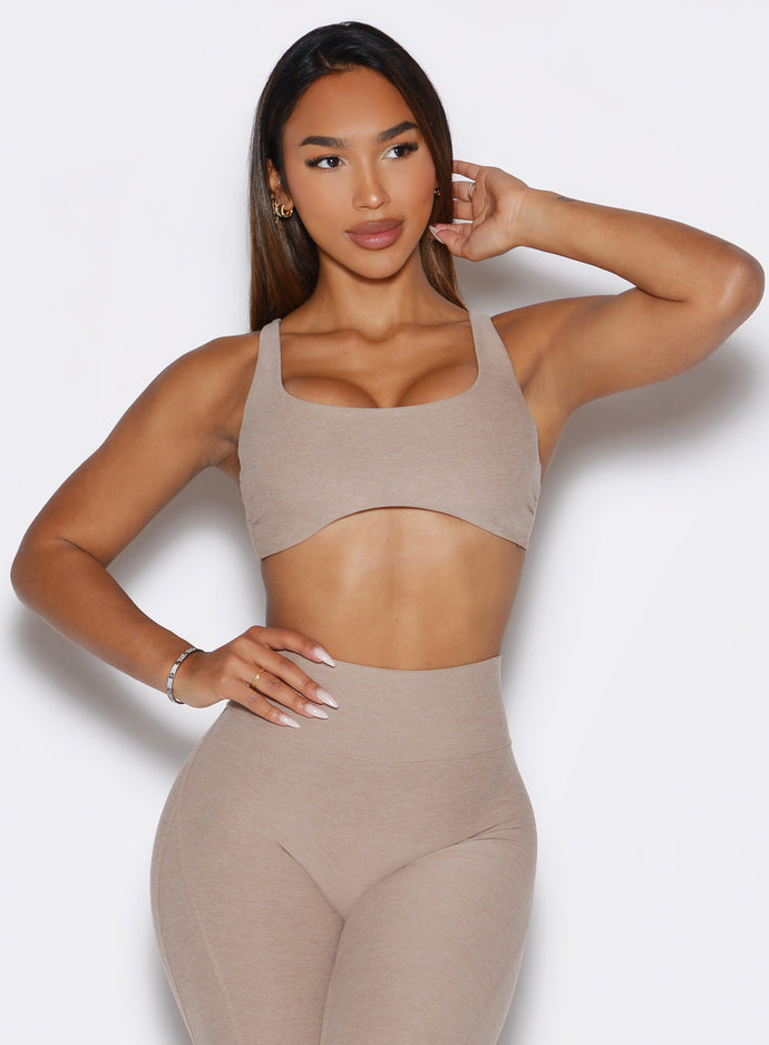 front profile view of a model with one hand on her waist and looking to the left  side wearing the Super set bra in desert taupe color
