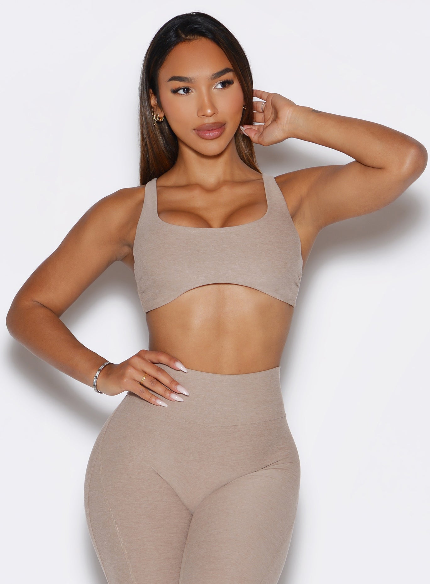 front profile view of a model with one hand on her waist and looking to the left  side wearing the Super set bra in desert taupe color