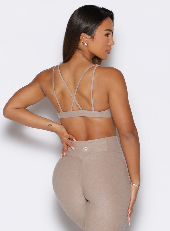 back profile view of a model with one hand on her waist wearing the Super set bra in desert taupe color