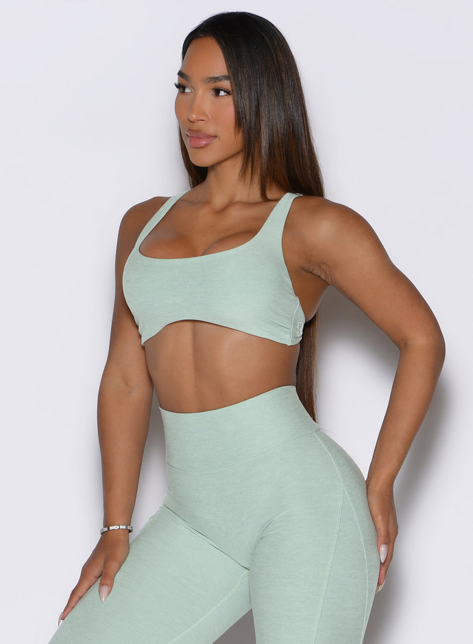 a frontal shot of a model looking to the right side wearing the super set bra in soft aloe color