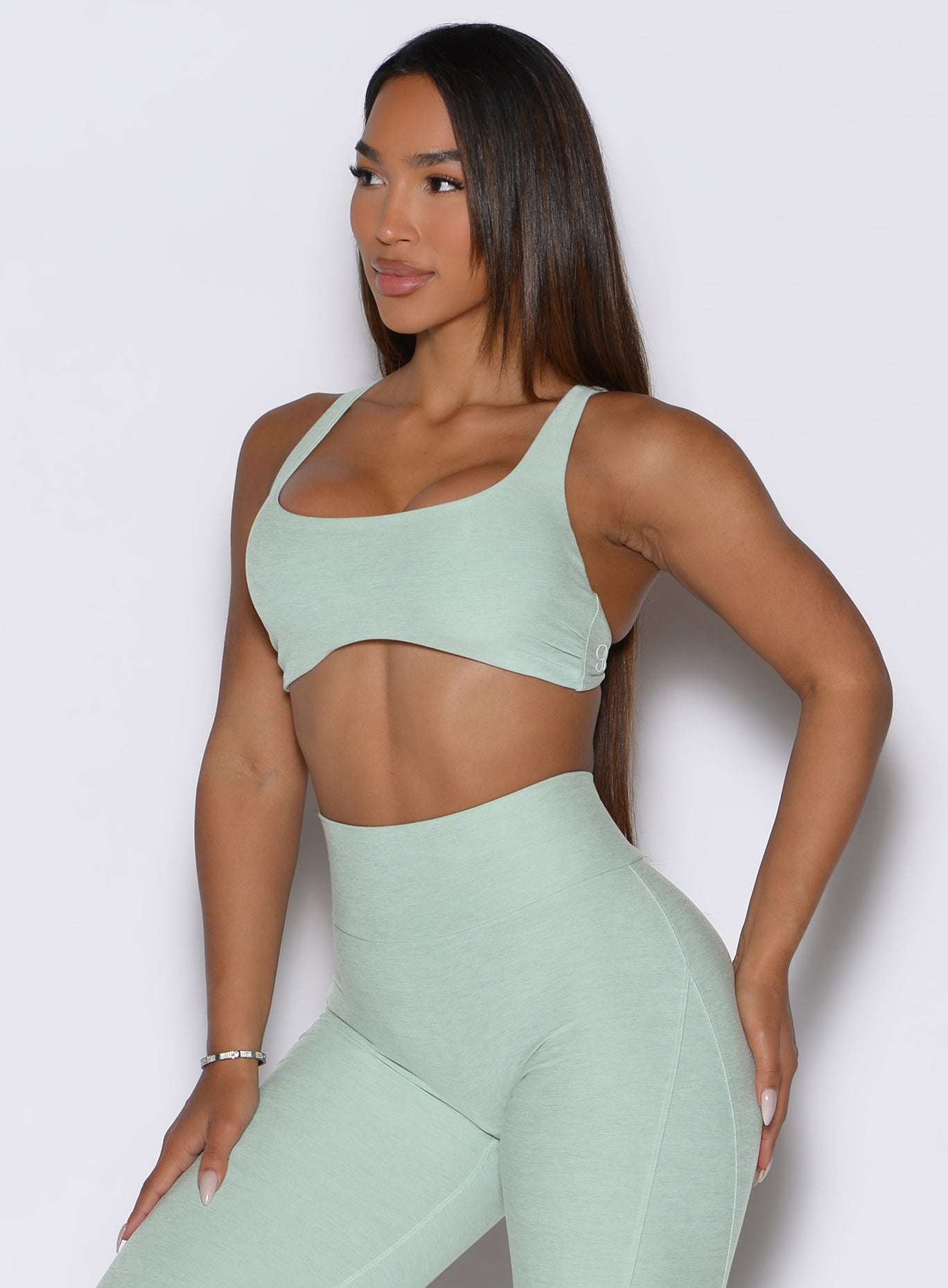 a frontal shot of a model looking to the right side wearing the super set bra in soft aloe color