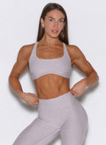front profile view of a model holding the waistband of the leggings with both hands wearing the Super set bra in violet ice color