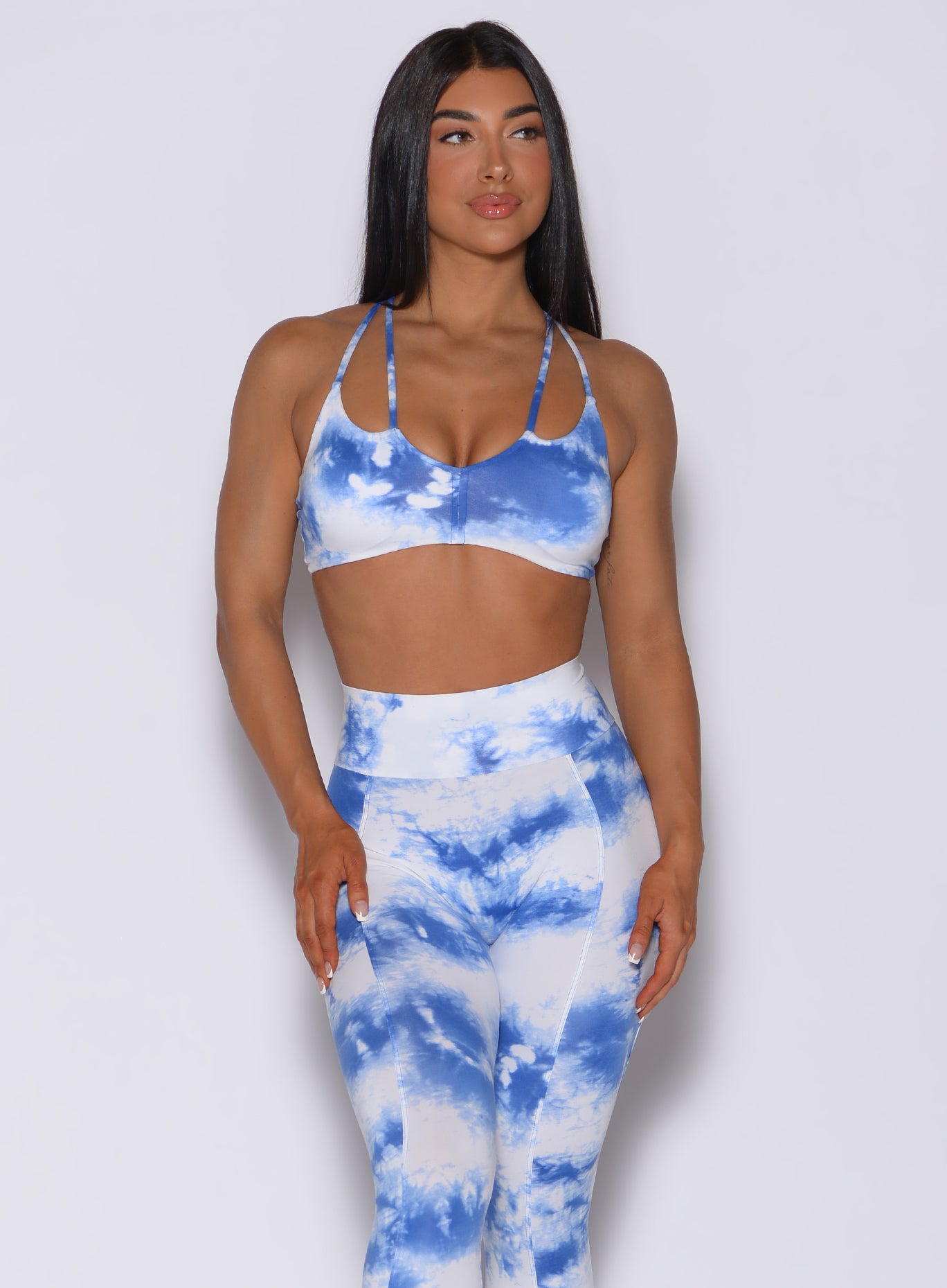 Picture of a model facing forward wearing our tie dye topnotch bra in white blue along with a matching leggings 
