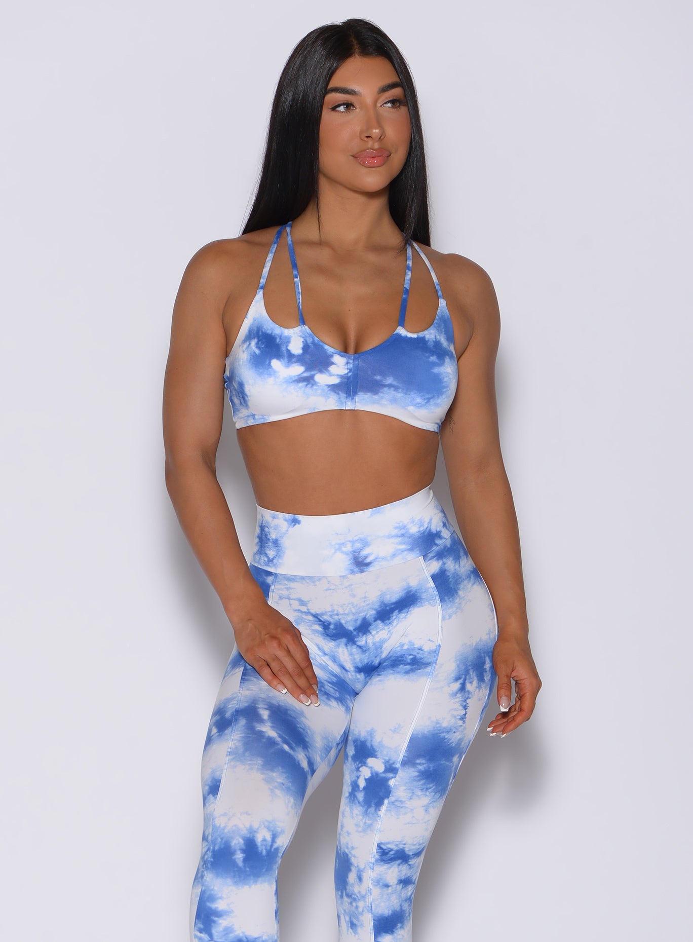 Front profile view of a model wearing our topnotch bra in tie dye white blue color and a matching tie dye leggings