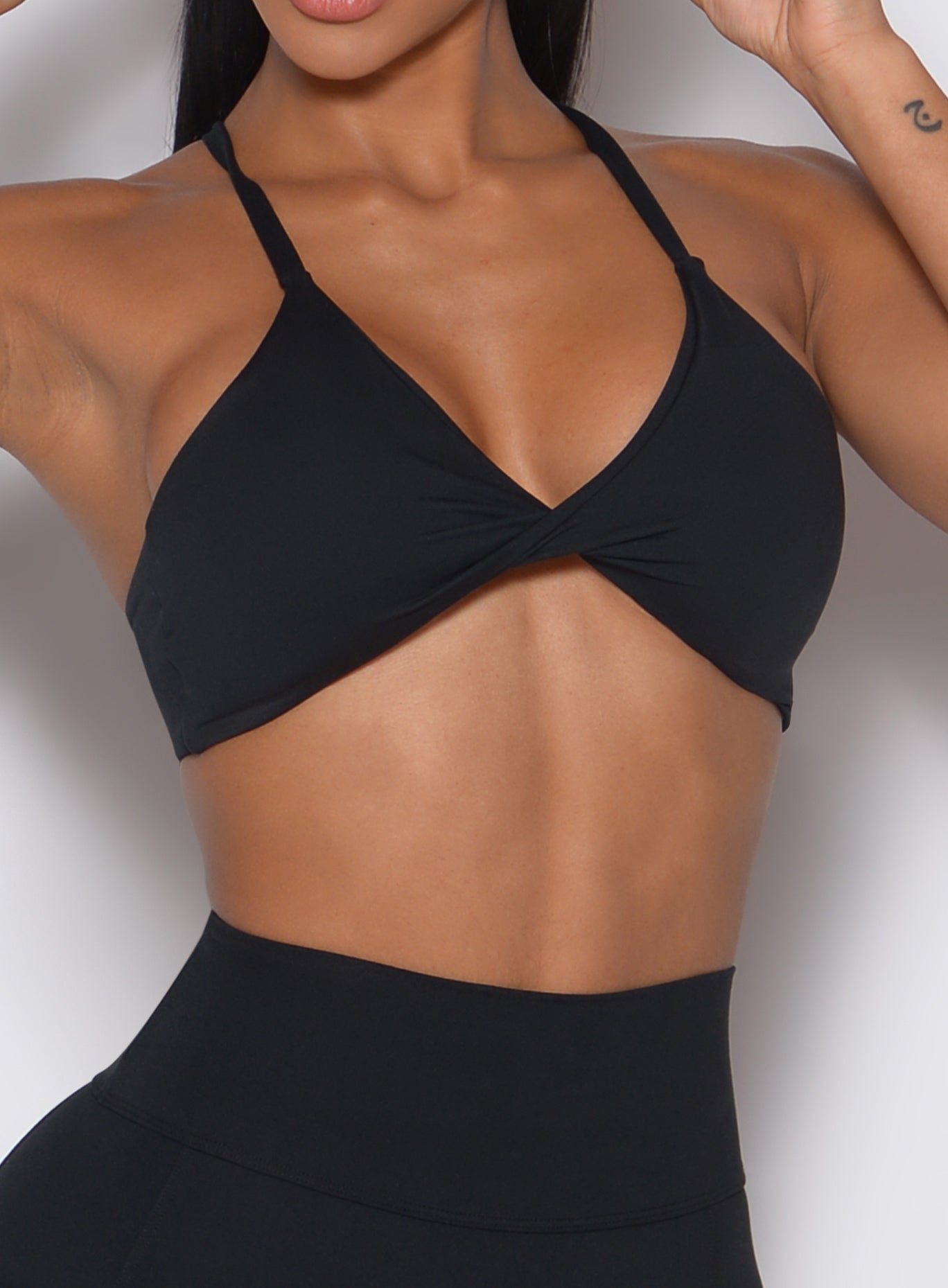 Zoomed in front profile view of a model waring our black Twist Mini Bra