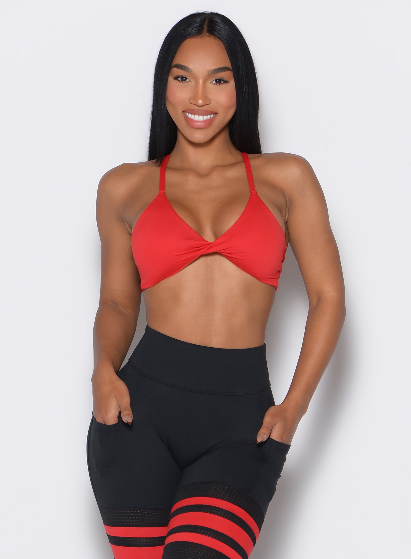 Front profile picture of a model wearing the Twist Mini Bra in Fire color complemented by a matching thigh high