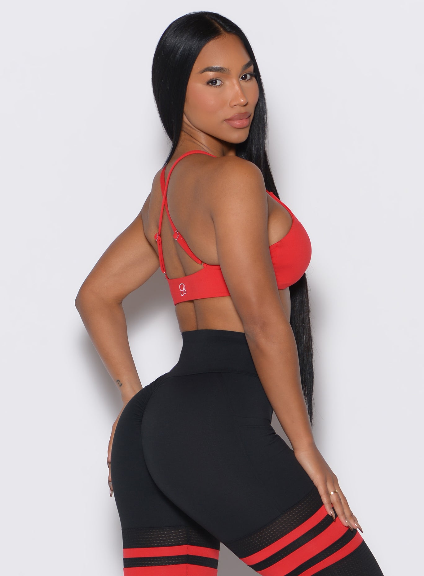 Back right-side profile shot of a model wearing the Twist Mini Bra in Fire color complemented by a matching thigh high