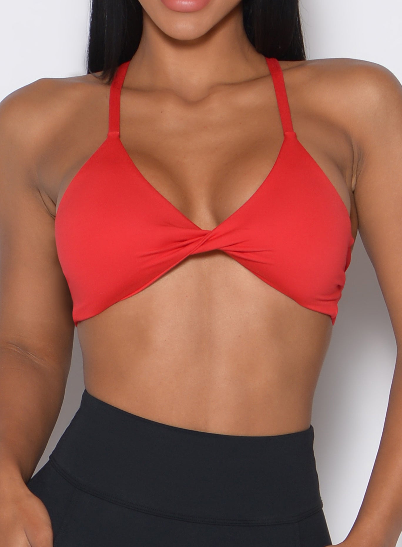 Zoomed in front profile view of a model wearing the Twist Mini Bra in Fire color