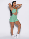 right side  profile view of a model wearing our tiny waist shorts in sage color along with the matching sports bra