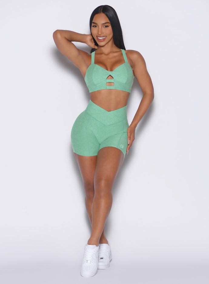 front profile view of a model wearing our tiny waist shorts in sage color along with the matching sports bra