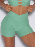 close up zommed in view of a model wearing our tiny waist shorts in sage color along with the matching sports bra