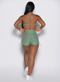 back profile view of a model wearing the Tiny Waist Tie Shorts in basil color