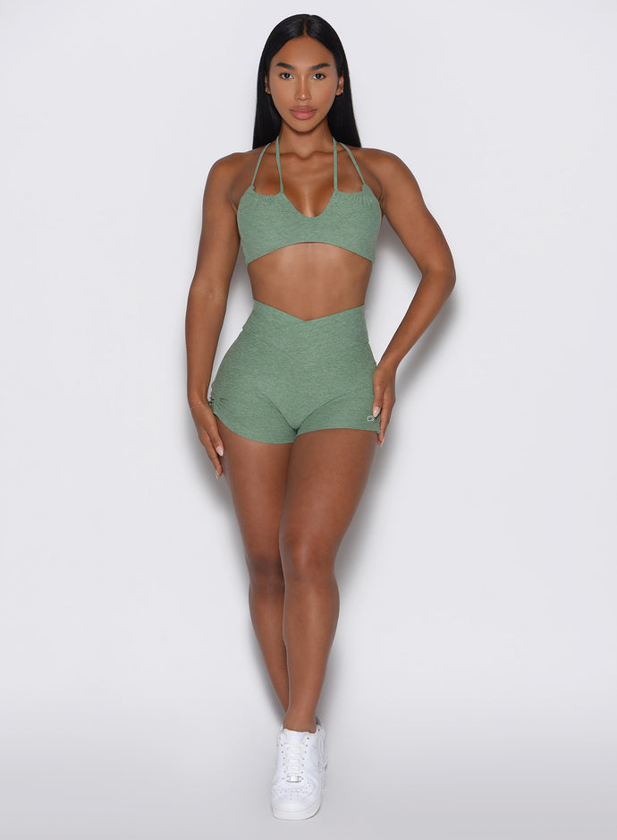 front profile view of a model with both hands resting on her thighs wearing the Tiny Waist Tie Shorts in basil color