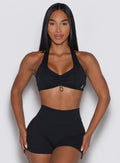 Woman wearing a black sports bra and shorts on a light gray background