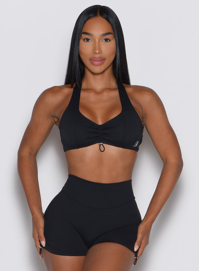Woman wearing a black sports bra and shorts on a light gray background