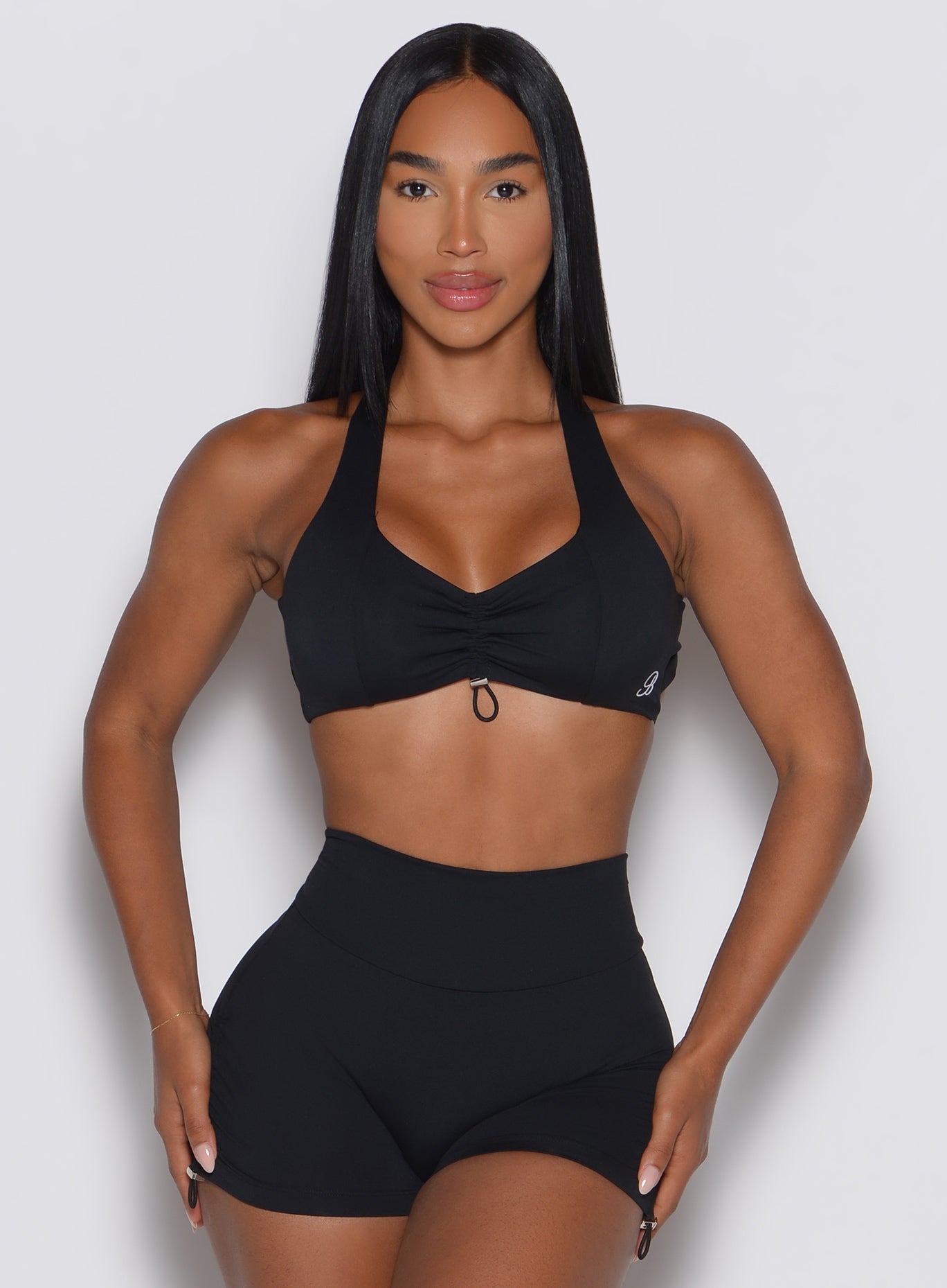 Woman wearing a black sports bra and shorts on a light gray background