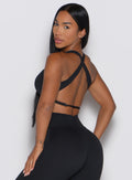 back left side profile view of a model looking over her shoulder wearing our Toggluxe Bra in black color